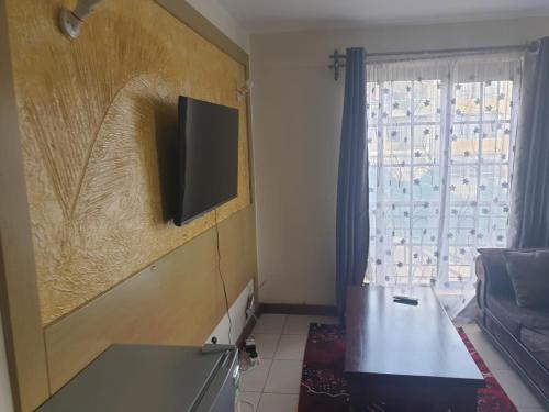 uma sala de estar com uma televisão de ecrã plano na parede em Mvuli suites em Nairobi