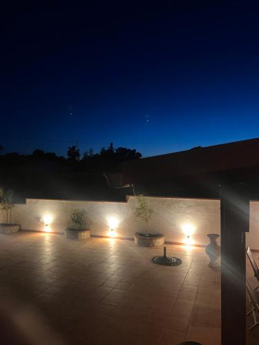 - une cour de nuit avec des lumières sur un mur dans l'établissement Villa gio puglia salento esclusiva villa privata con 6 camere doppie 3 bagni posti auto terrazza giardino 5 minuti dal mare, à San Pietro in Bevagna