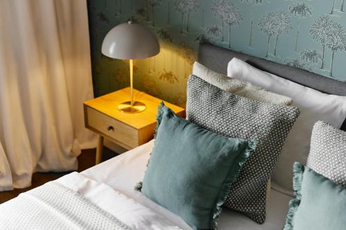 a bed with pillows and a lamp on a table at Cracow Palm Apartment in Kraków