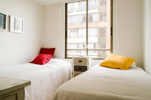 2 camas con almohadas rojas y amarillas en una habitación en Excelente 4 personas, cerca del Metro ycentro, en Santiago