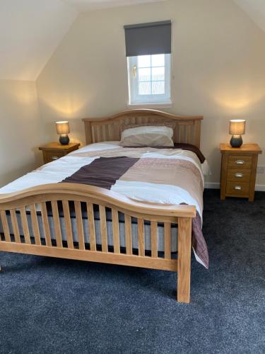 1 dormitorio con 1 cama grande de madera y 2 mesitas de noche en WHITEHILL STABLES, en Kirknewton