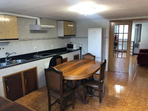 eine Küche mit einem Holztisch und einigen Stühlen in der Unterkunft La casita del Bierzo in Carracedelo