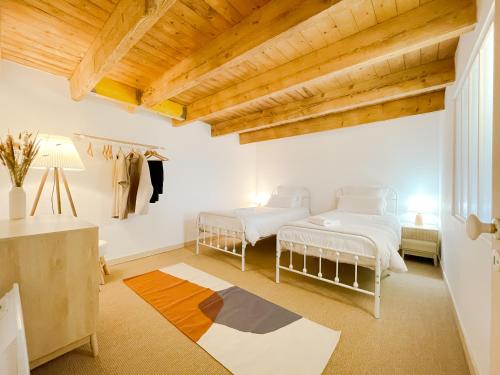 two beds in a room with wooden ceilings at La Maison de Léon in Saint-Georges-de-Gréhaigne