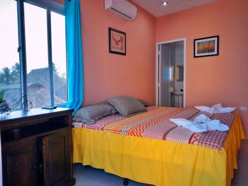 1 dormitorio con 1 cama con paredes de color naranja y ventana en Hotel el Paredon, en El Paredón Buena Vista