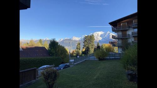 a view of a yard with a house and mountains at La marmotte: Vue Mont Blanc, terrasse, parking in Combloux