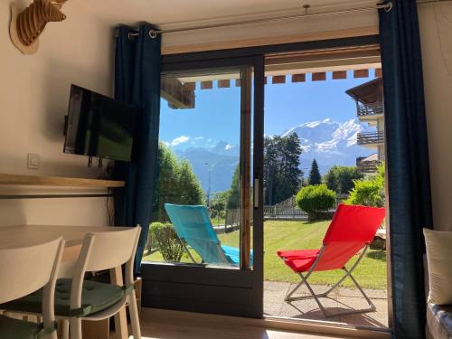 a room with a sliding glass door with colorful chairs at La marmotte: Vue Mont Blanc, terrasse, parking in Combloux