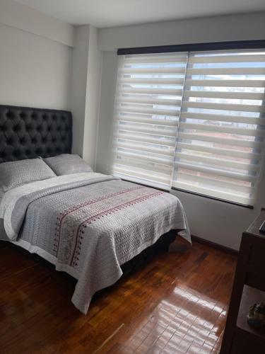 ein Schlafzimmer mit einem Bett und einem großen Fenster in der Unterkunft Habitación en Casa Loma in Cochabamba