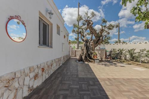 a building with a tree next to a wall at Extravacanza Polignano a Mare in Polignano a Mare