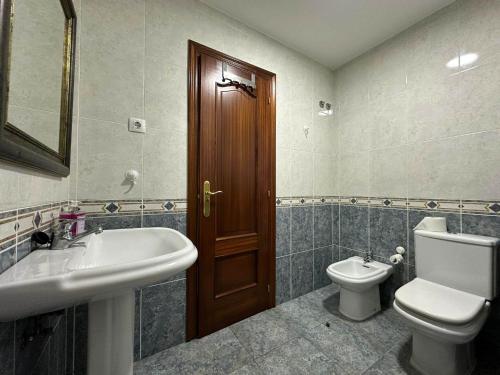 baño con lavabo, aseo y puerta en Vendaval, en Muxía