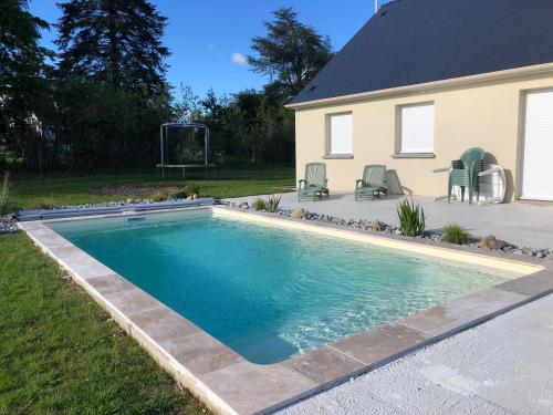 a swimming pool in a yard next to a house at Maison les coquelicots in Garennes-sur-Eure