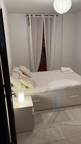 a white bedroom with a bed and a table at La Casa del Tambor in Córdoba