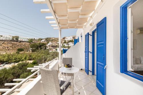uma varanda com portas azuis e uma mesa e cadeiras em Platis Gialos beach house with sea view balcony em Platis Gialos, Mykonos