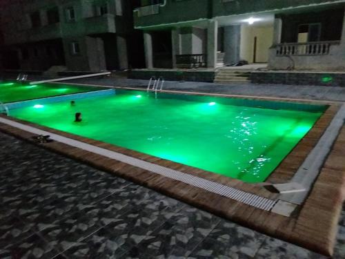 a swimming pool lit up green at night at شقه مصيف للايجار بكمبوند عجيبه سيتي مرسي مطروح in Zâwyet Umm el Rakham