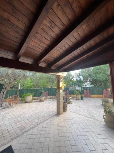 a patio with a wooden roof with potted plants at Villa Azzurra Fronte Mare in Capitana