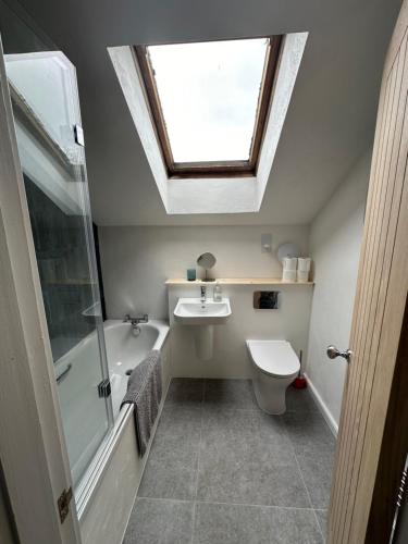 een badkamer met een wastafel en een dakraam bij The Coach House North Wales, Amazing views , hot tub, log fire in Halkyn