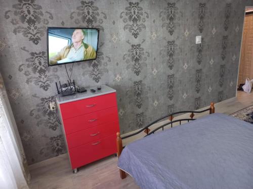 Комфортные аппартаменты في كاراغاندي: غرفة نوم مع خزانة ملابس حمراء مع تلفزيون على الحائط