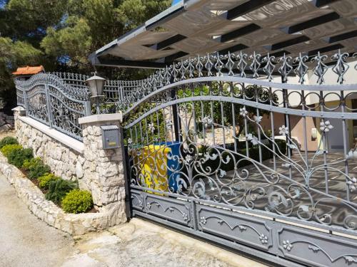 a wrought iron gate with a stone wall at Apartments Annie in Rogoznica