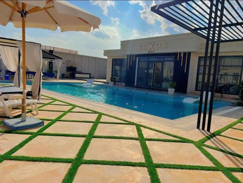 a swimming pool with an umbrella next to a building at Tixos Farm in Irbid