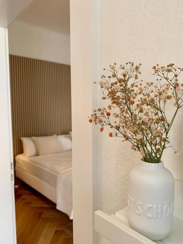 a white vase with flowers sitting on a shelf next to a bed at Stilvoll wohnen am St. Johanner Markt in Saarbrücken