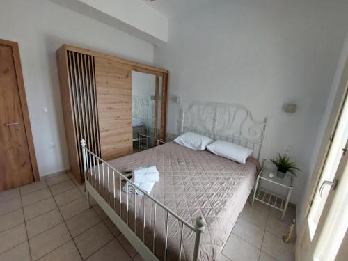 a bedroom with a white bed with a wooden headboard at Maritina's house in Vroutsi in Amorgos