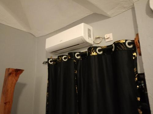 Zimmer mit einem TV und einem Duschvorhang in der Unterkunft Opaque gardens in Tezo