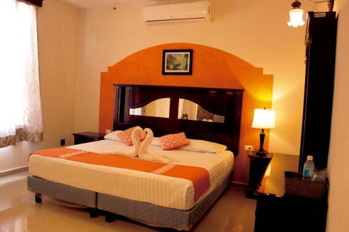 a bedroom with a large bed with a large headboard at Hotel Quinta Marciala MX in Valladolid