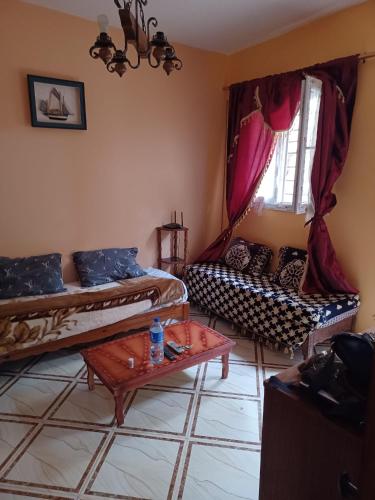 MAISON DE VACANCE في Mostaganem: غرفة معيشة بسريرين وطاولة