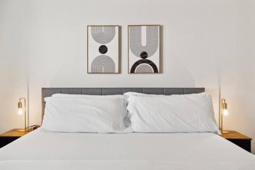 a bedroom with a white bed with two pictures on the wall at Gleaming Contemporary Home in Buckeye with Pool,BBQ in Buckeye