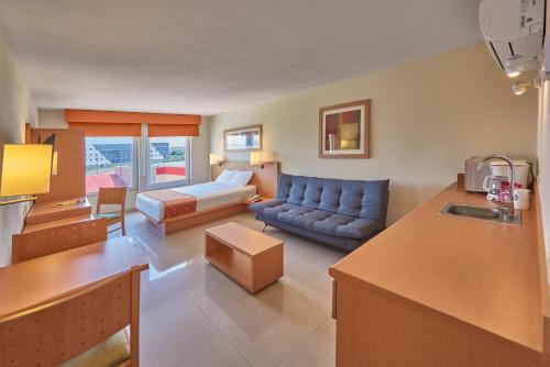 City Express by Marriott Mazatlan في مازاتلان: غرفة معيشة مع أريكة وغرفة معيشة مع أريكة