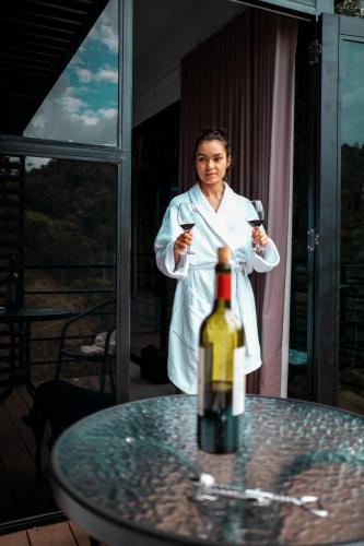 Uma mulher de roupão branco com dois copos de vinho. em Gaia Elegancia Escarlata extra 2 em San Rafael