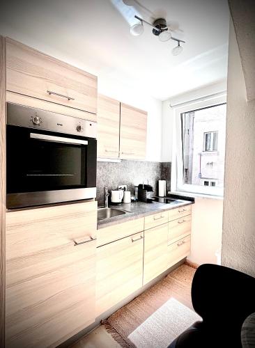 a kitchen with wooden cabinets and a microwave at Franziskaner Suites #6 in Graz