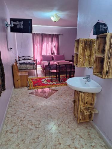 a bathroom with a sink and a living room at Maison Touria in Ouzoud