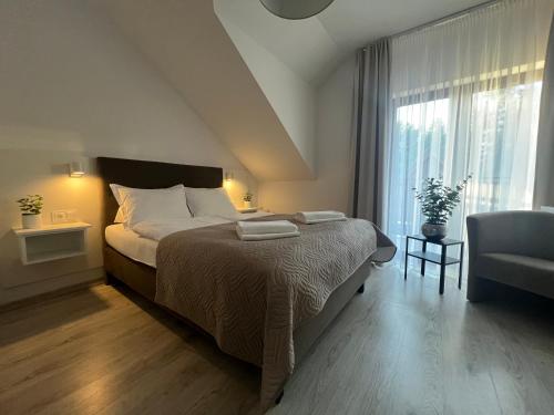1 dormitorio con 1 cama, 1 silla y 1 ventana en Ostoja, en Dębki