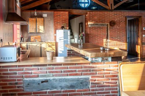 eine Küche mit Ziegelwand und Kühlschrank in der Unterkunft La casa de forja in Tarilonte