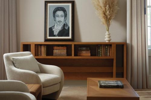 a living room with a book shelf with a portrait of a man at Plaza San Antonio Hotel & Spa, Autograph Collection in San Antonio