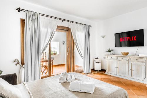 una stanza bianca con un letto e una tv di PORTO CERVO-CALA DEL FARO [Parking-Sea-Garden] a Porto Cervo