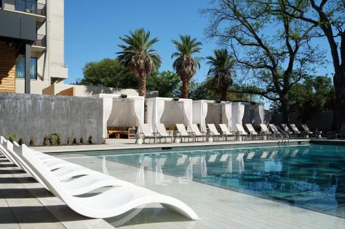 a swimming pool with white lounge chairs and trees at Plaza San Antonio Hotel & Spa, Autograph Collection in San Antonio