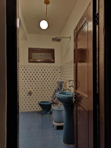 a bathroom with a blue sink and a toilet at The Kailasha Homestay in Nagar