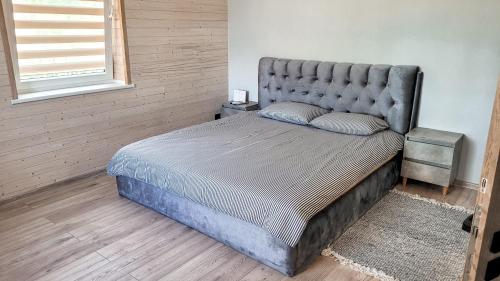 a bed with a tufted headboard in a bedroom at Butas ant ežero kranto in Telšiai