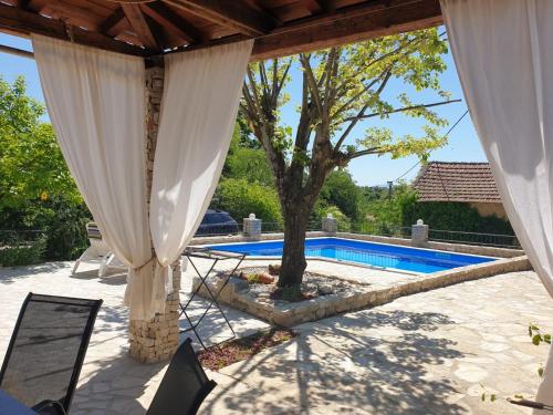 un patio con una mesa, un árbol y una piscina en “House Botić”, 