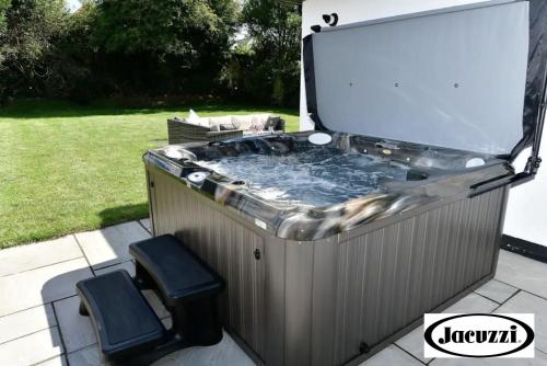 a jacuzzi tub with two chairs in a yard at Heatherslade House - Hot Tub, Dog Friendly in Parkmill
