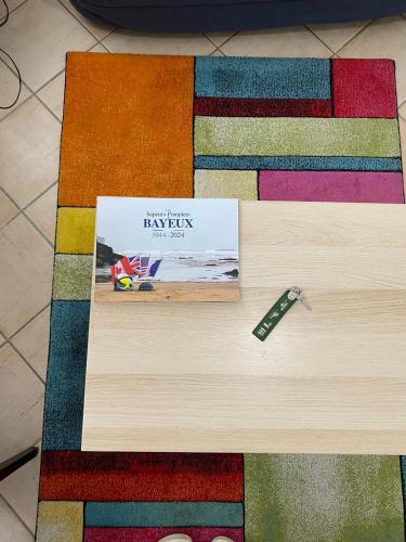 une table avec un livre sur un tapis coloré dans l'établissement BAYEUX DDAY 80e STUDIO à côté de la Cathédrale, à Bayeux