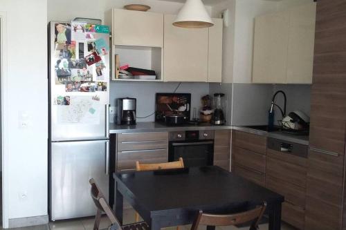Il comprend une cuisine équipée d'une table noire et d'un réfrigérateur. dans l'établissement Idéal JO - Appartement - Résidence Les Parisiennes, à Aubervilliers