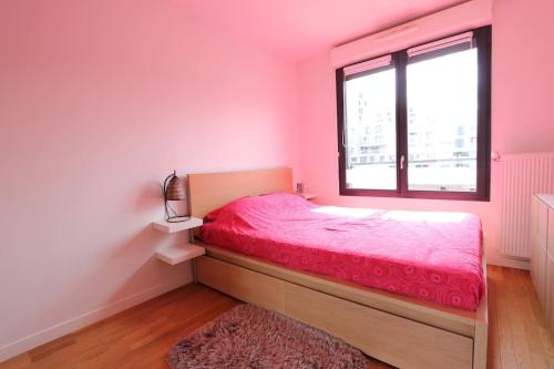 1 dormitorio con cama rosa y ventana en Appartement calme et lumineux proche Paris, en Asnières-sur-Seine