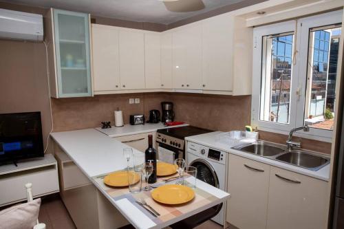 a kitchen with white cabinets and a table with glasses on it at Downtown Lavrio Port Cozy Apt in Lávrion