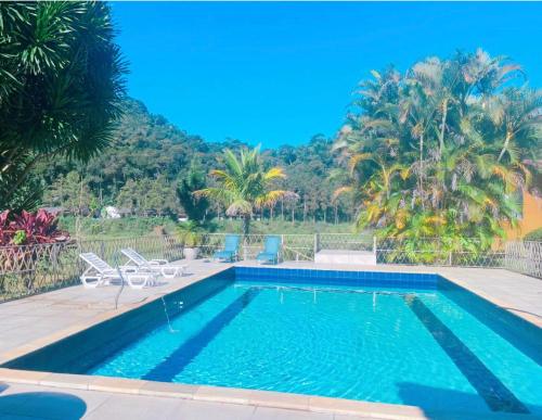 a swimming pool with palm trees and a mountain in the background at Pousada Jupter in Teresópolis