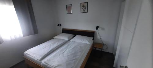 ein kleines Schlafzimmer mit einem Bett mit weißer Bettwäsche in der Unterkunft Costa Plana Lipno in Černá v Pošumaví