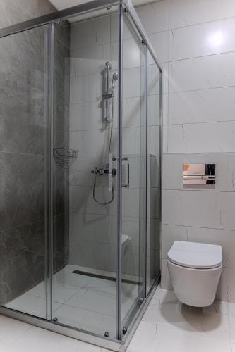 a bathroom with a glass shower with a toilet at Home Art Apartments in Skopje