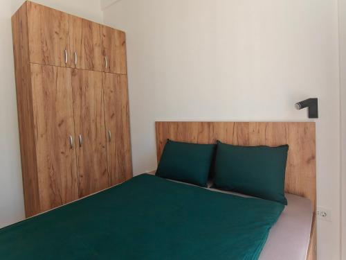 a bedroom with a bed with green sheets and wooden cabinets at Home Art Apartments in Skopje