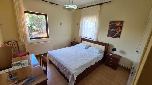 a bedroom with a bed and a desk and a window at Stella Keramies Apartment in Keramiaí